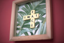 Load image into Gallery viewer, Framed wall art collage with Tropical leaf background and "twat face" written in scrabble tiles