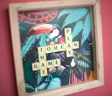 Load image into Gallery viewer, Characterful and colourful scrabble art with a rainforest design background and 'Toucan Play That Game' written in vintage scrabble tiles presented in a natural wooden box frame