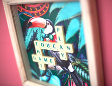 Load image into Gallery viewer, Characterful and colourful scrabble art with a rainforest design background and 'Toucan Play That Game' written in vintage scrabble tiles presented in a natural wooden box frame