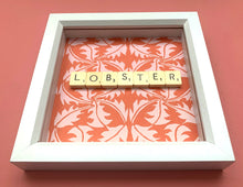 Load image into Gallery viewer, Characterful and colourful scrabble art with red patterned paper background and 'Lobster' written in vintage scrabble tiles presented in a white box frame