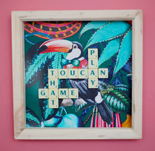 Load image into Gallery viewer, Characterful and colourful scrabble art with a rainforest design background and 'Toucan Play That Game' written in vintage scrabble tiles presented in a natural wooden box frame