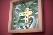 Load image into Gallery viewer, Framed wall art collage with Tropical leaf background and &quot;twat face&quot; written in scrabble tiles 
