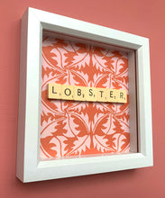 Load image into Gallery viewer, Characterful and colourful scrabble art red patterned background with &#39;Lobster&#39; written in vintage scrabble tiles presented in a white box frame 
