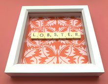 Load image into Gallery viewer, Characterful and colourful scrabble art with red patterned paper background and &#39;Lobster&#39; written in vintage scrabble tiles presented in a white box frame 
